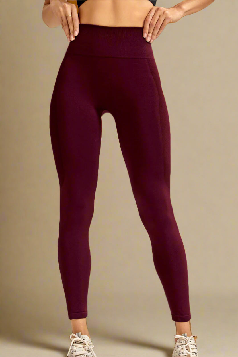 Person wearing maroon leggings standing against a neutral background
