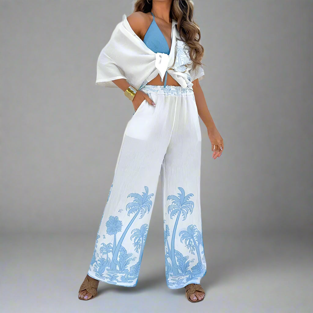 Woman wearing a white outfit with blue palm tree patterns in a bright setting
