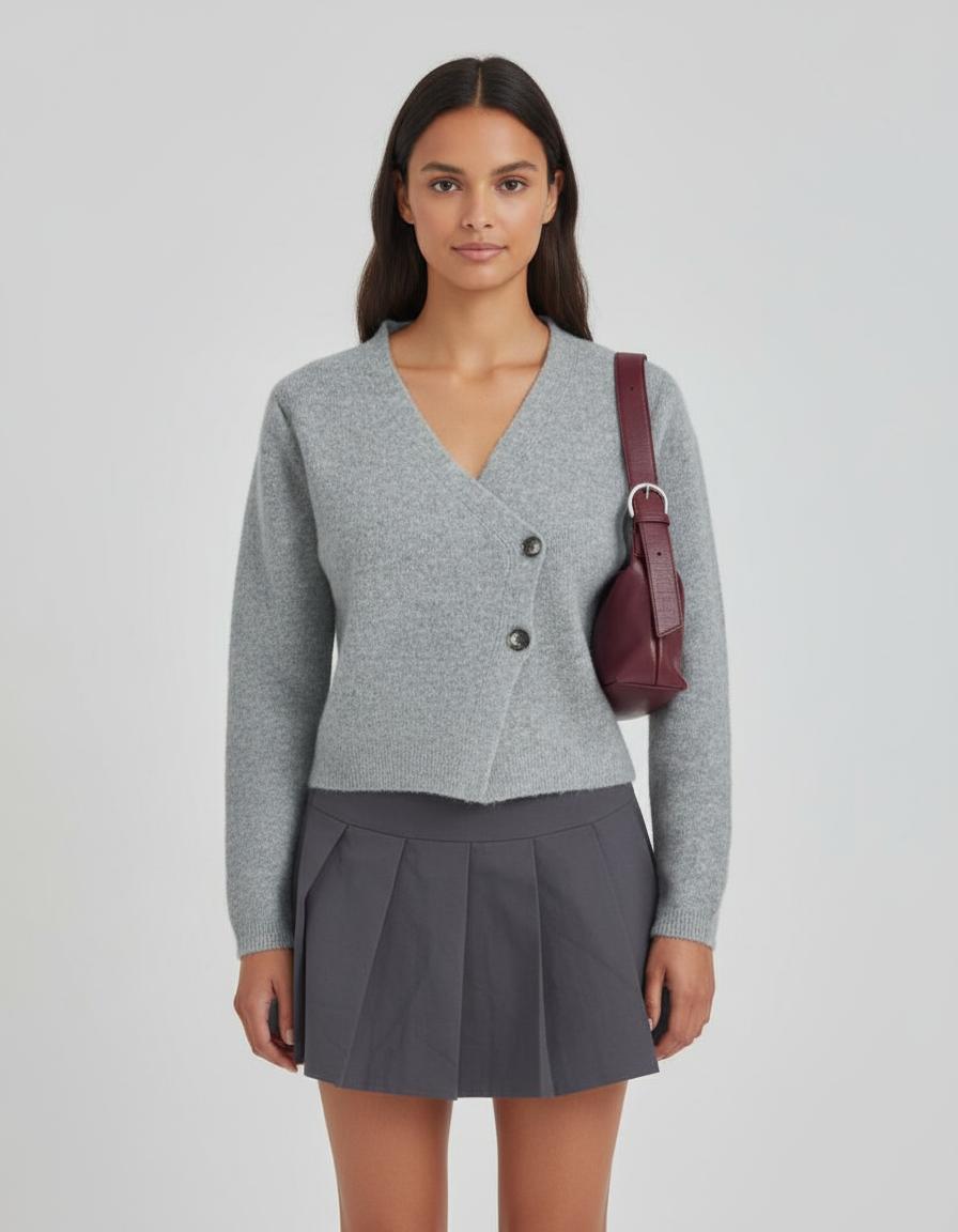 Woman wearing a gray cardigan and skirt with a maroon handbag on a light gray background