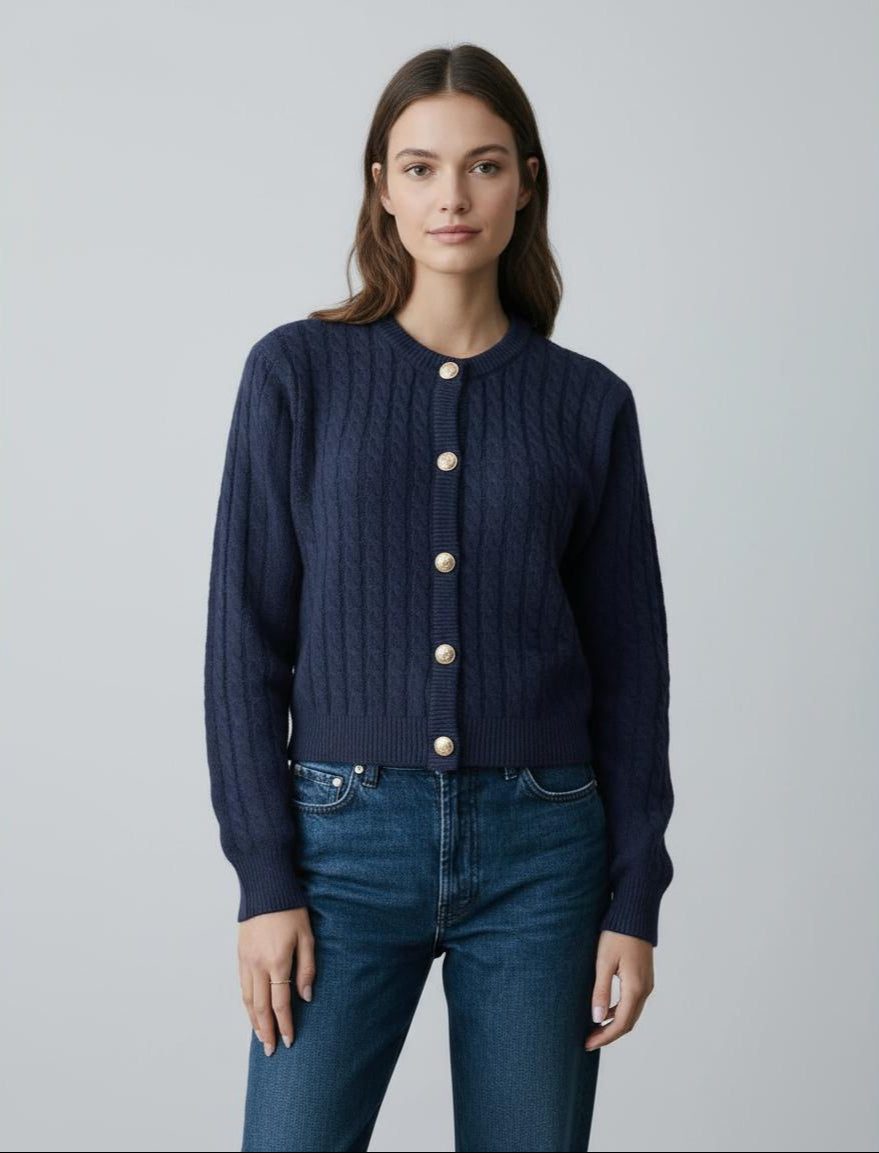 Woman wearing a navy blue cardigan with gold buttons and jeans on a light gray background
