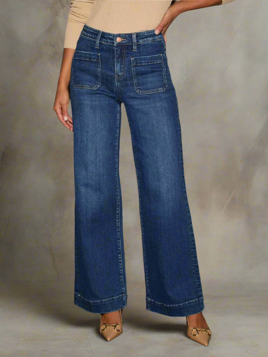 Person wearing blue wide-leg jeans against a textured wall.