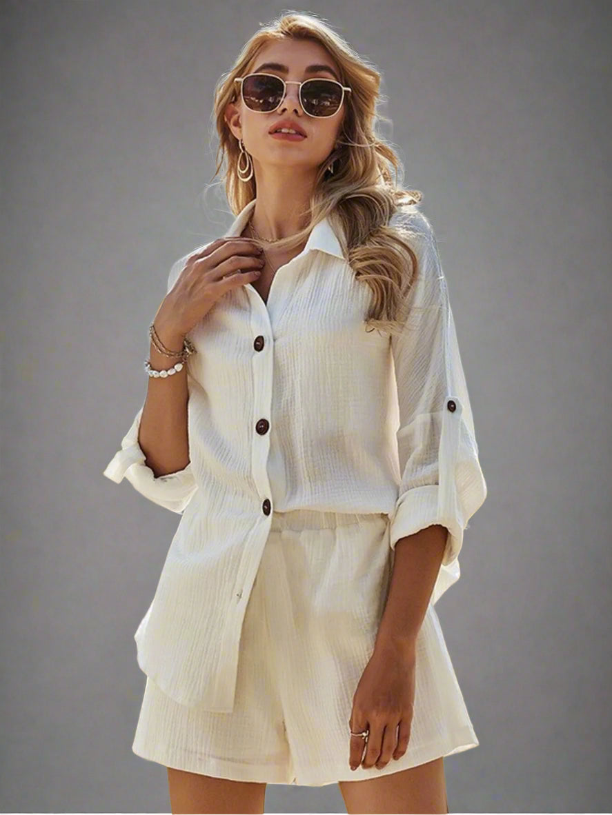 Woman in a white outfit with sunglasses standing in a studio setting