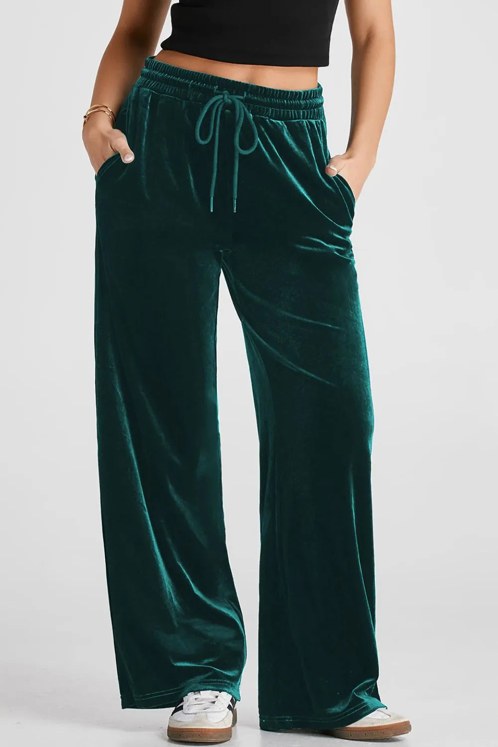 Green velvet pants worn by a person on a white background