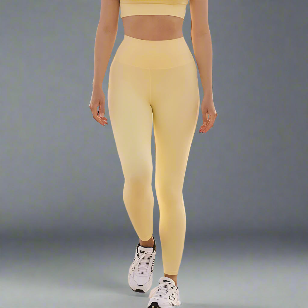 Person wearing yellow leggings and a sports bra on a beach.