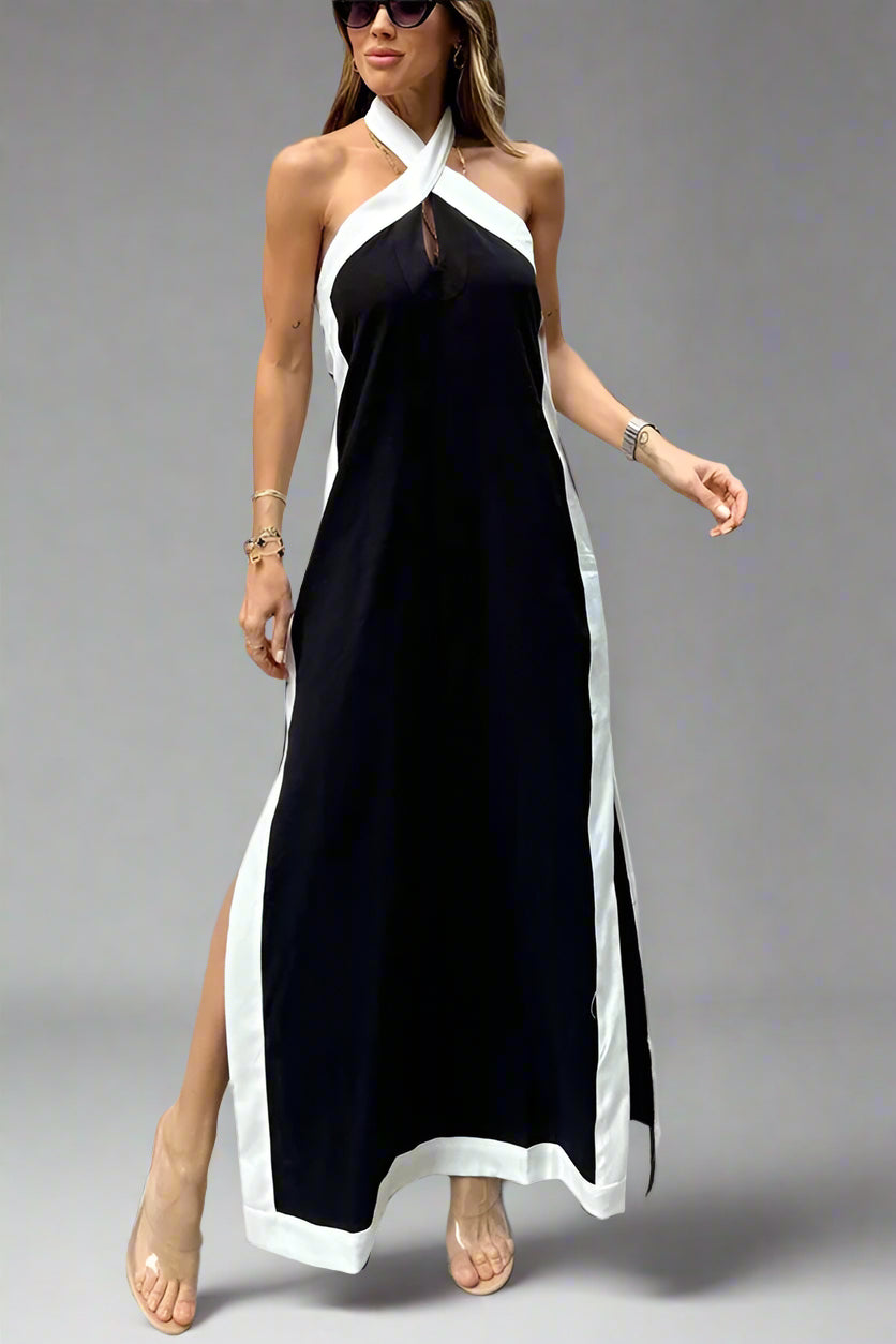 Woman wearing a black and white halter neck dress with a high slit on a plain background