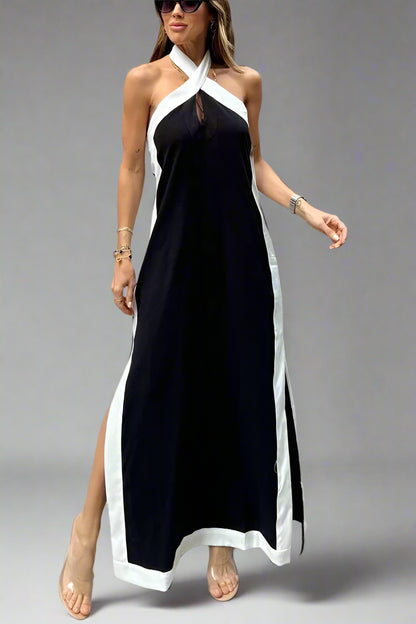 Woman wearing a black and white halter neck dress with a high slit on a plain background