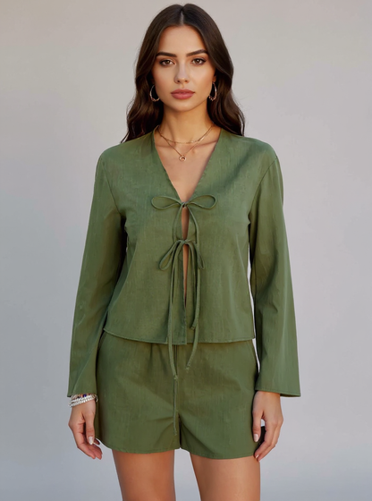 Woman wearing a green long-sleeve top and shorts set on a plain background