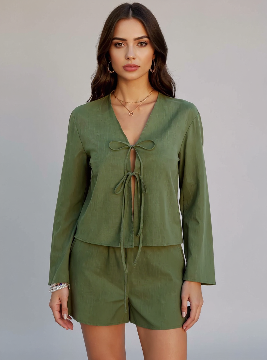 Woman wearing a green long-sleeve top and shorts set on a plain background