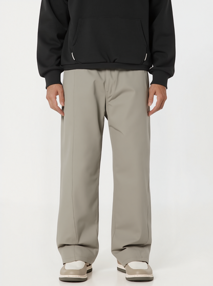 Person wearing a black hoodie and beige pants on a white background