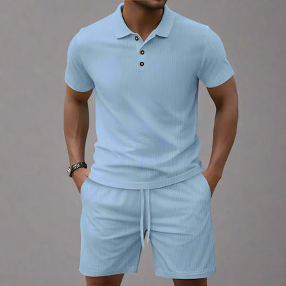 Man wearing a light blue polo shirt and shorts set on a blurred background