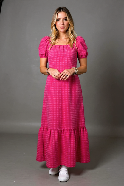 Woman wearing a pink checkered dress against a gray background
